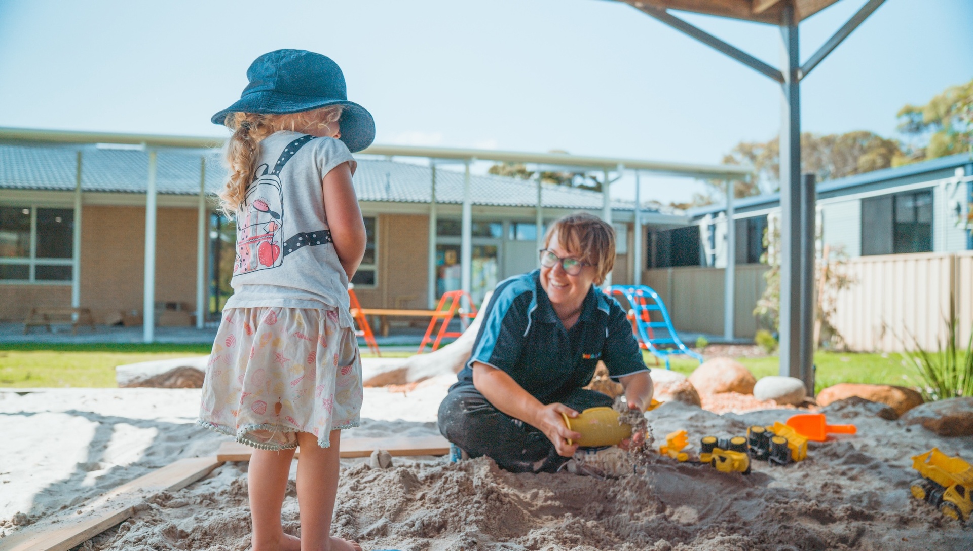 Young child and childcare worker playing in sandpitSmartPlay Albany Sandpit
