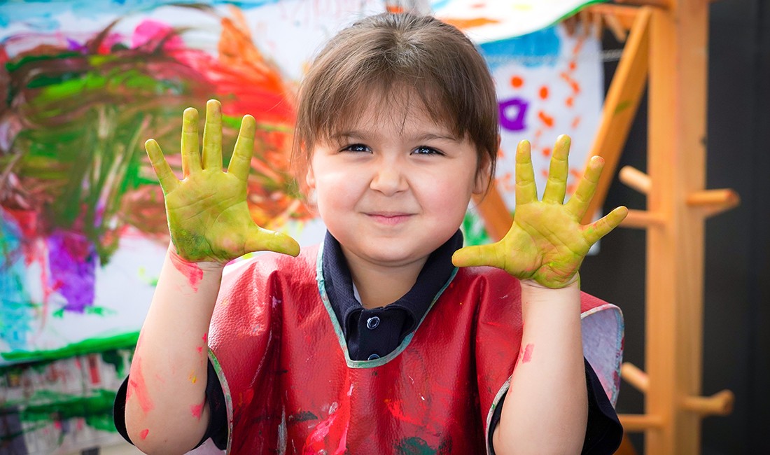 painting girl-in-smockat early learning center