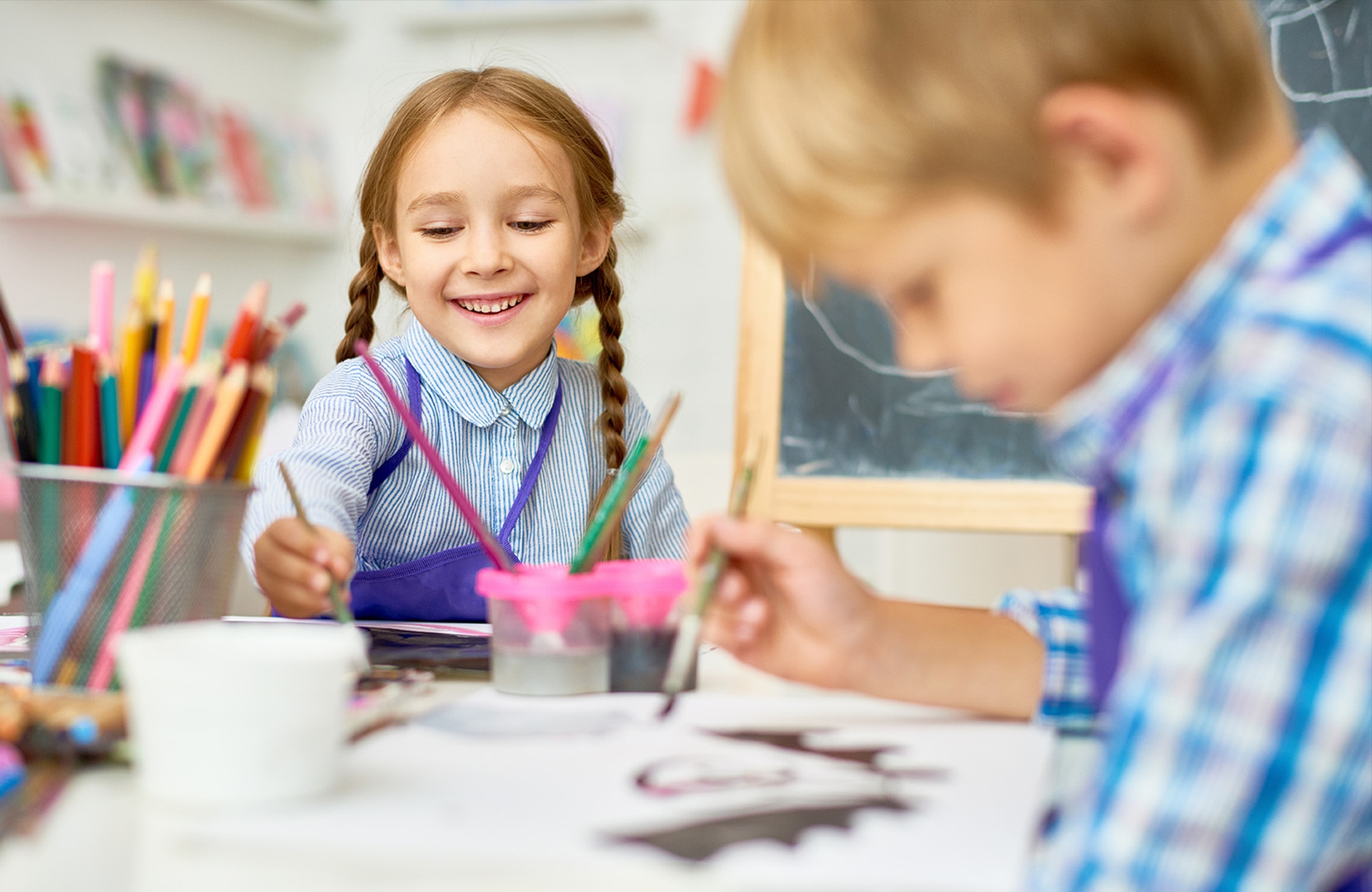 Early learners boy and girl at table smiling and painting