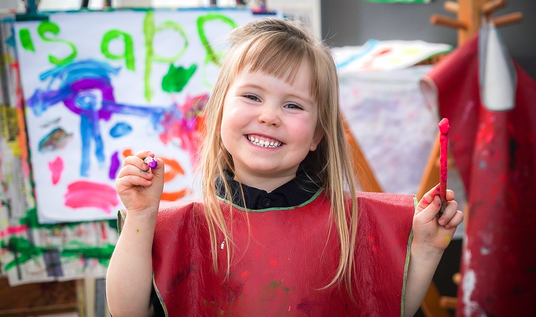 smiling girl-in-smockat early learning center